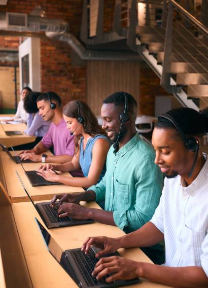 Multi-Cultural Customer Support Or Telesales Team In Modern Open Plan Office Wearing Headsets